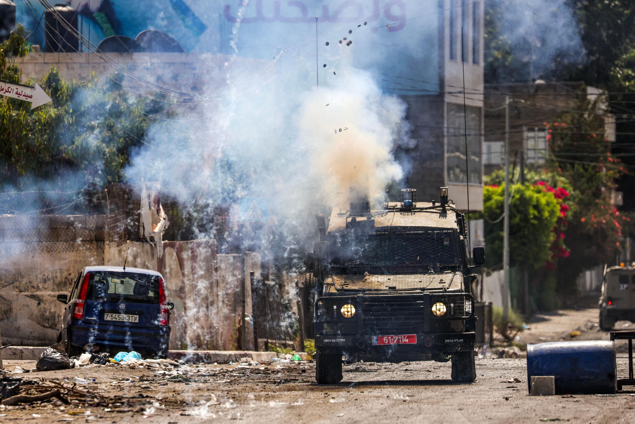 TOPSHOT - Israeli soldiers fire tear gas canisters from an armoured vehicle during an ongoing military operation in the occupied West Bank city of Jenin on July 4, 2023. Israel pushed on for a second day on July 4 with its biggest military operation in