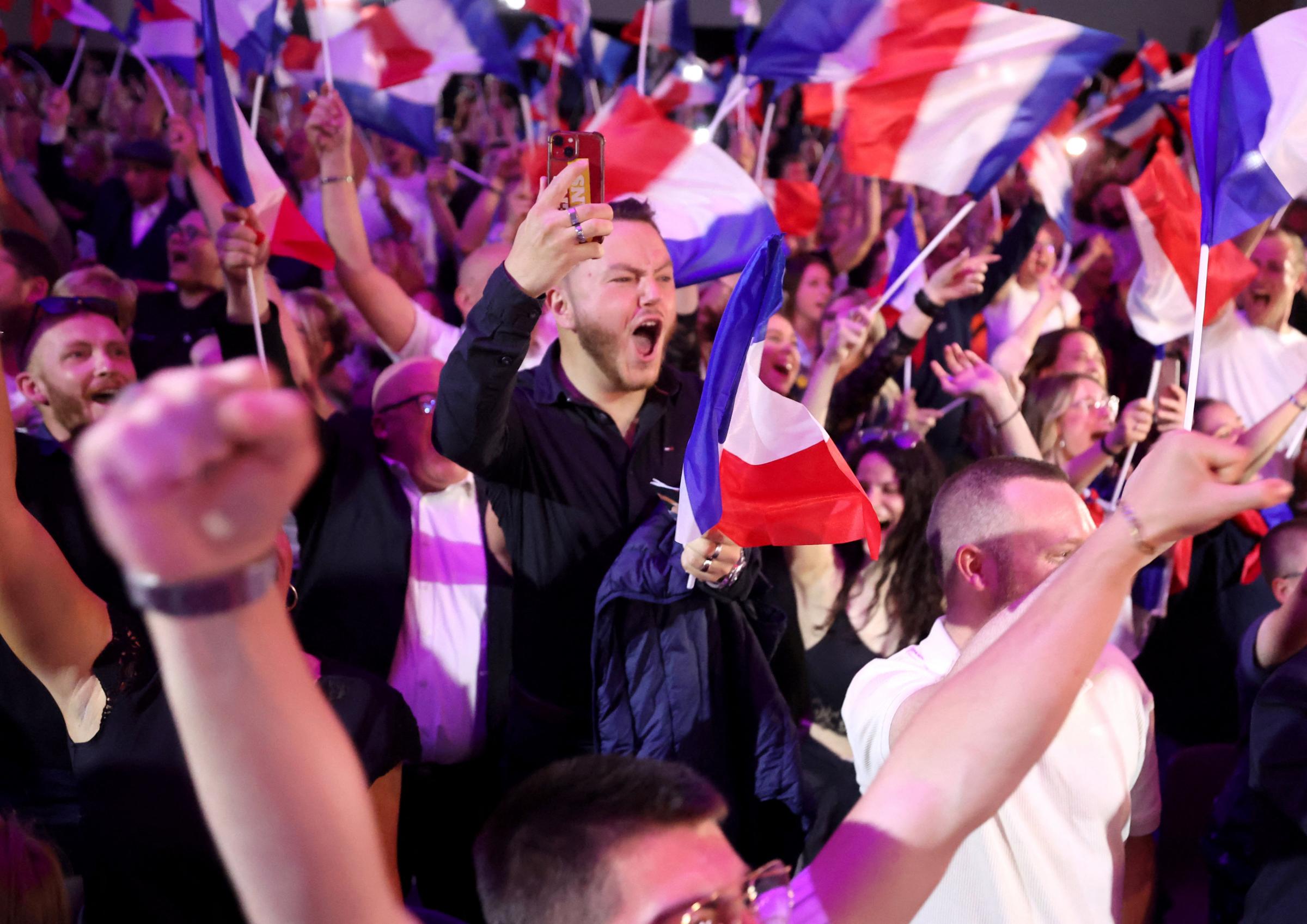 TOPSHOT - Supporters react as former president of the French far-right Rassemblement National (RN) parliamentary group Marine Le Pen gives a speech during the results evening of the first round of the parliamentary elections in Henin-Beaumont, northern
