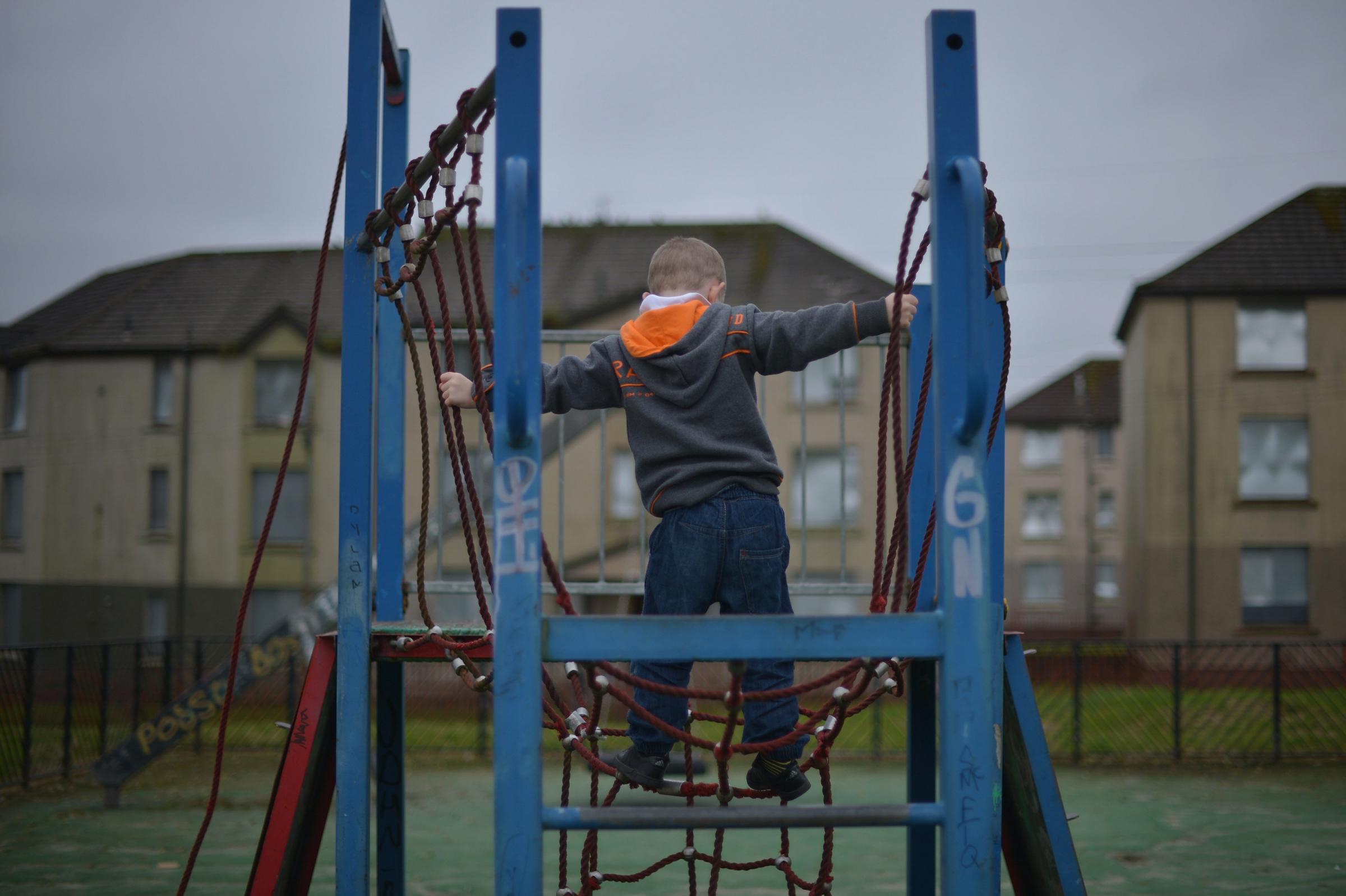 GLASGOW, SCOTLAND - OCTOBER 23: A young boy plays in a play park near disused housing in the Hamiltonhill area on October 23, 2012 in Glasgow, Scotland. The Scottish National Party (SNP) have announced a welfare fund to provide emergency support to