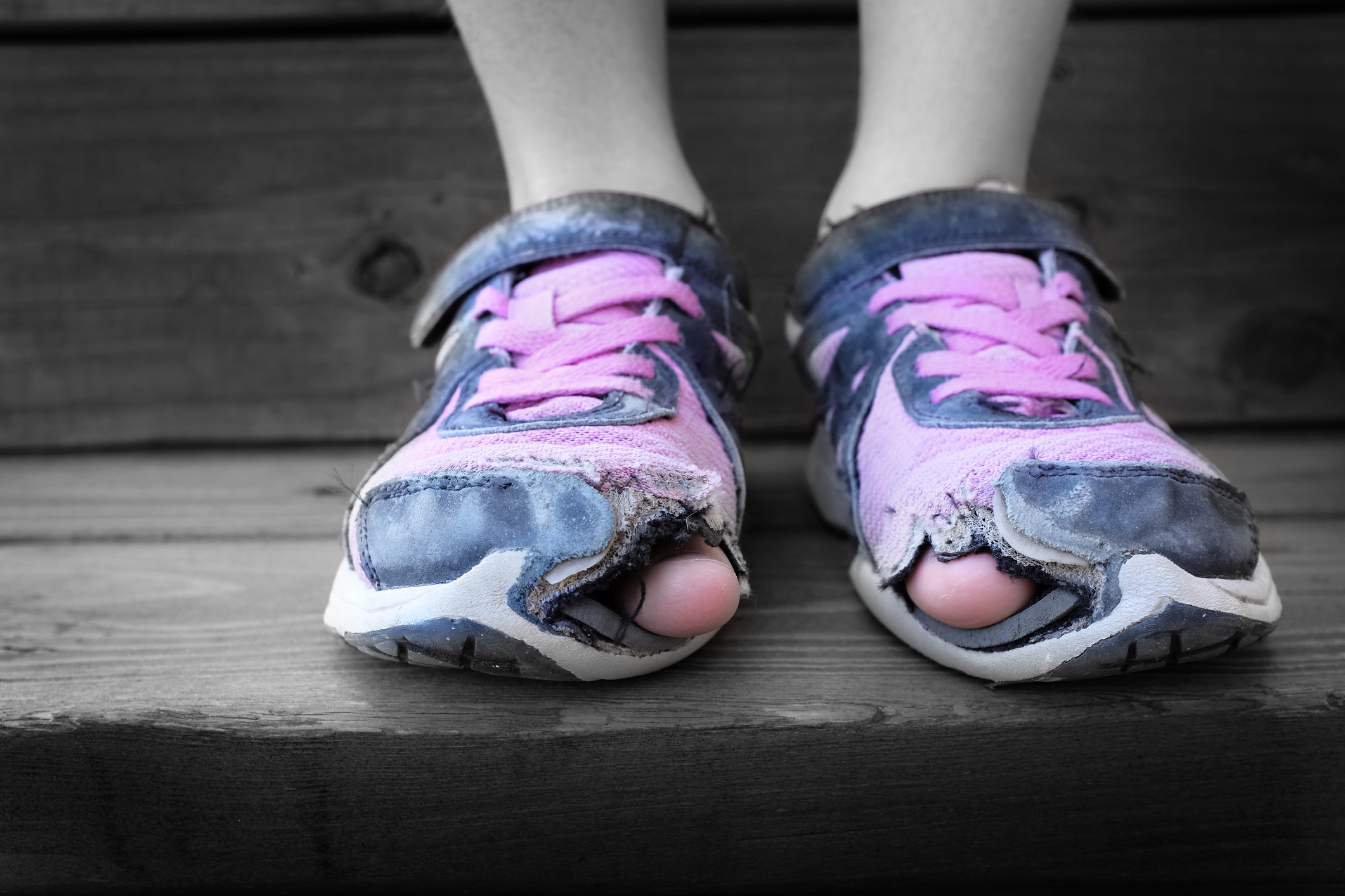 Worn out old shoes with holes in the toes used by homeless child