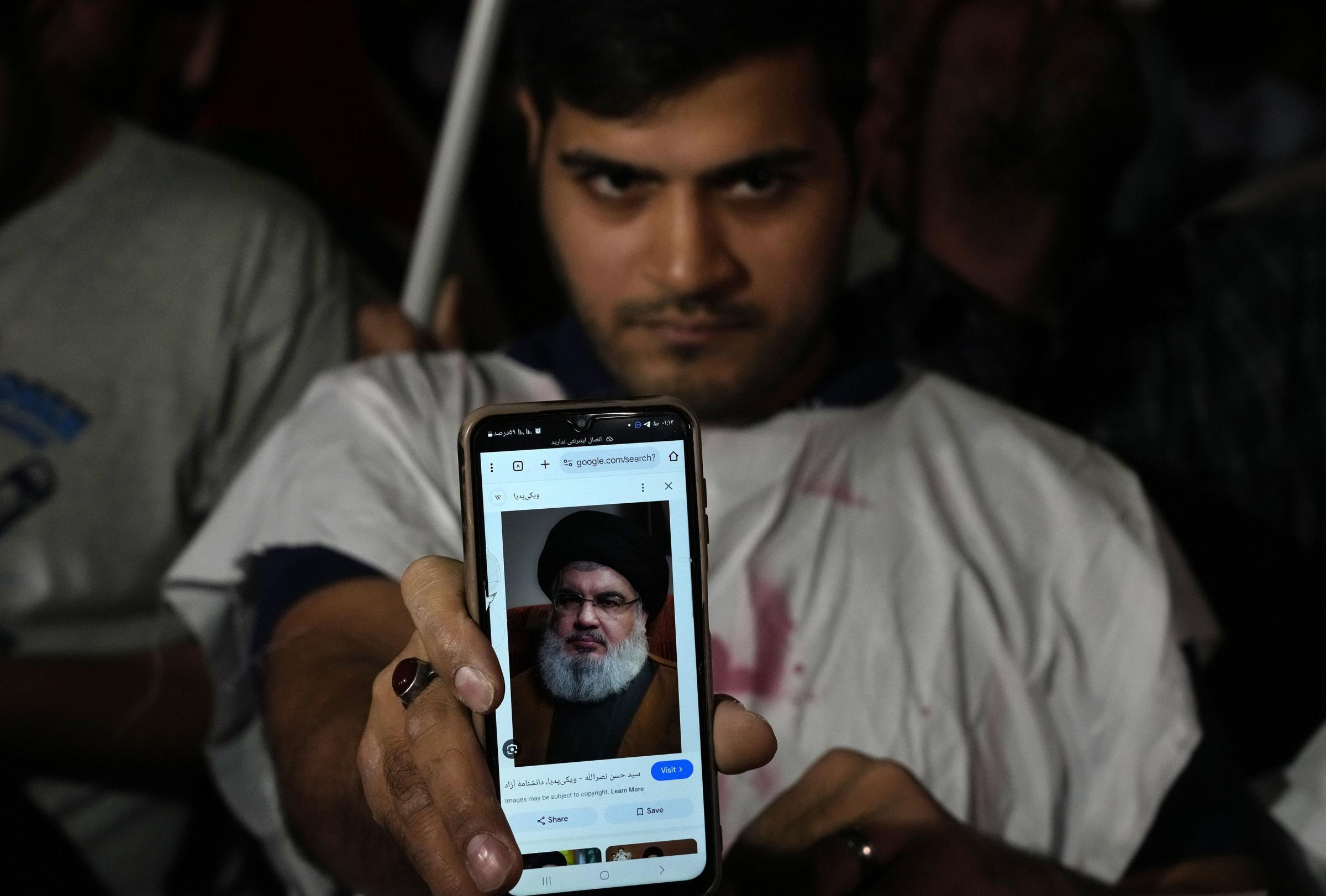 An Iranian demonstrator shows a portrait Hezbollah leader Hassan Nasrallah on his cell phone during a demonstration in support of Hezbollah at the Felestin (Palestine) Square in downtown Tehran, Iran, early Saturday, Sept. 28, 2024. (AP Photo/Vahid