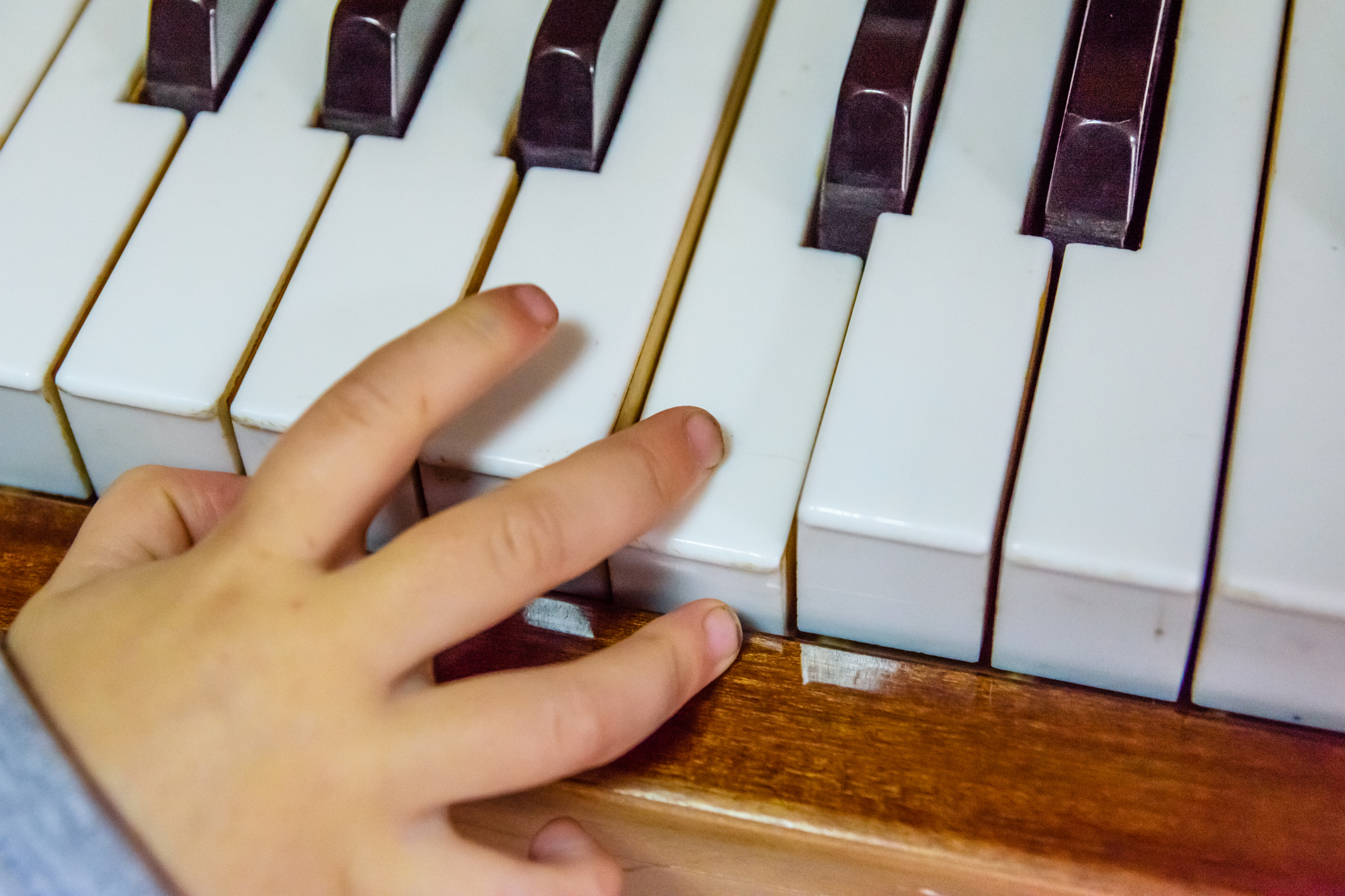 Child hand on a shiny piano keys